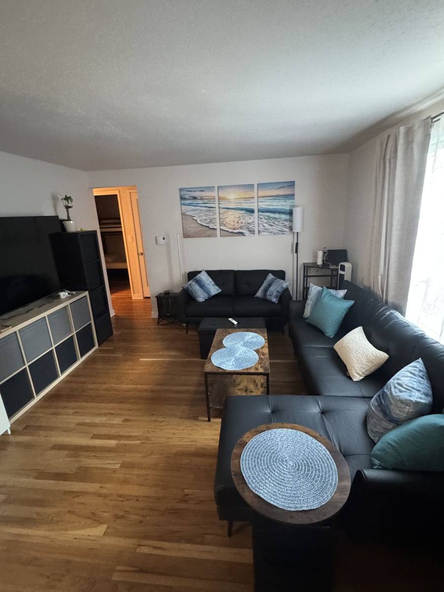 Living room with sectional sofa, TV and hardwood floors